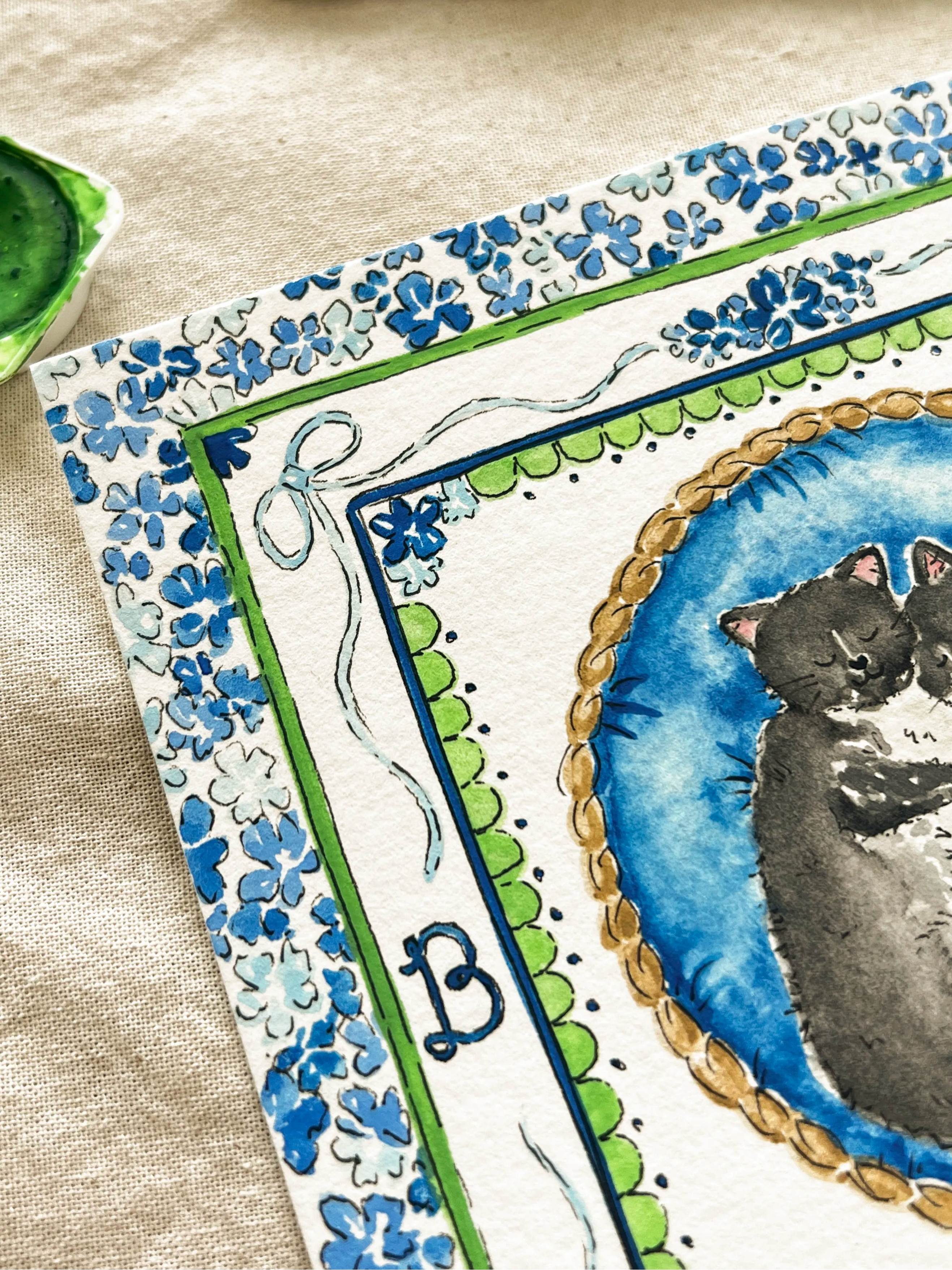 Artistic depiction of a cat in a decorative frame with a brush and green paint on a beige background